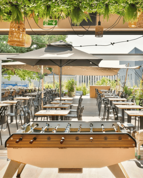 Notre terrasse XXL ensoleillée avec baby-foot et grandes tablées.