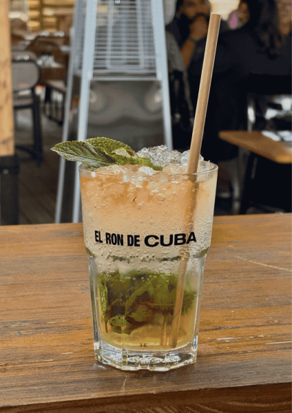 Verre de Mojito avec décorations alimentaires posé sur le bar extérieur avec terrasse XXL en arrière-plan.