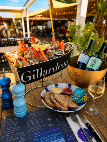 Photo plateau de fruits de mers, bouteilles de vins blanc et terrasse au soleil.
